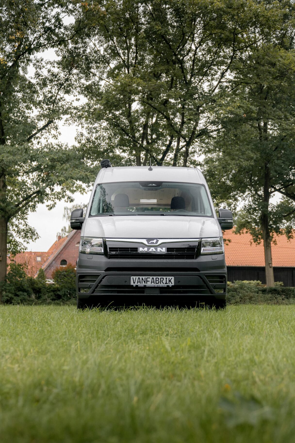 Frontansicht eines weißen MAN TGE auf einer grünen Wiese