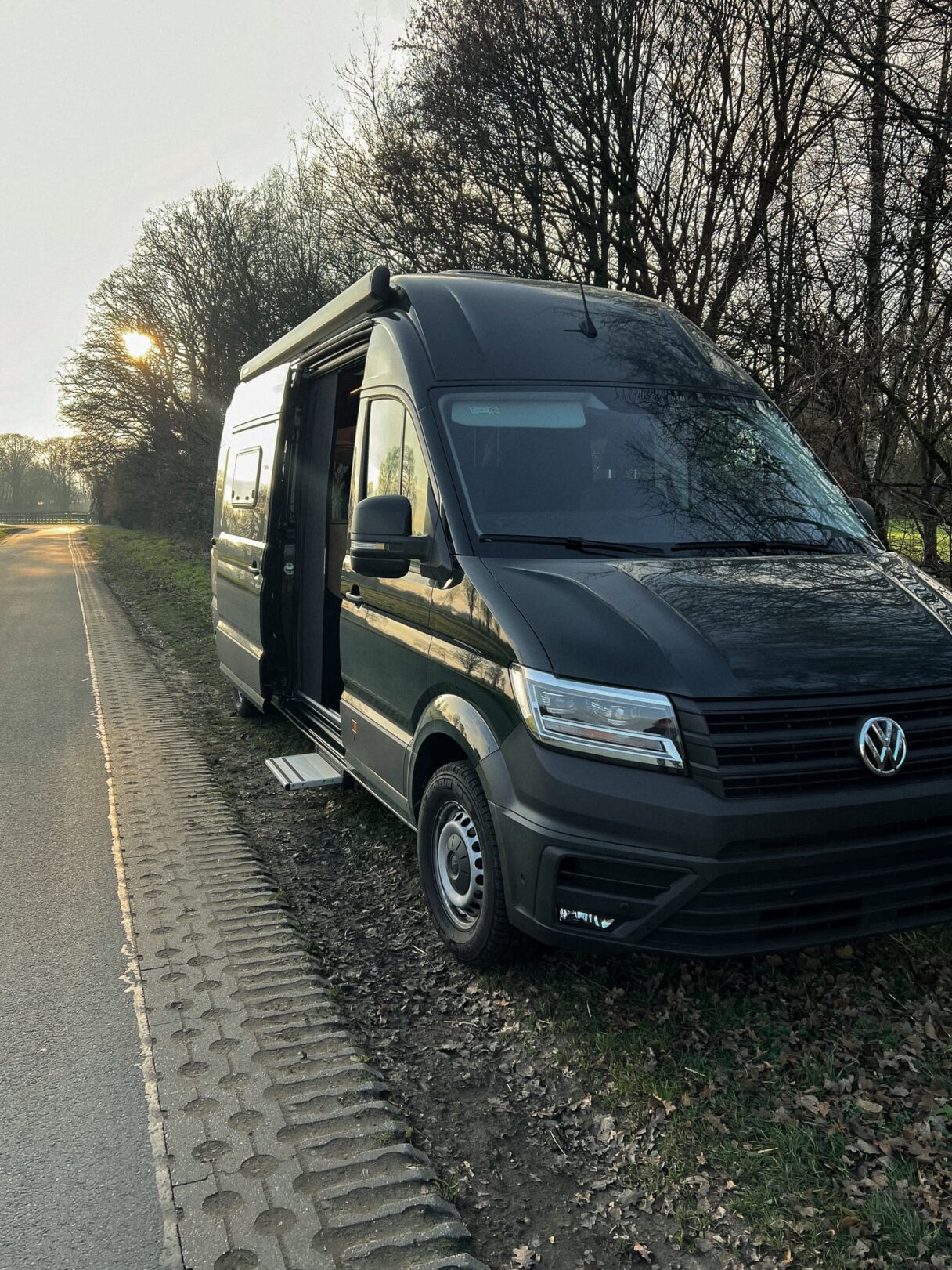 Schwarzer VW Crafter, der mit einer offenen Seitentüre am Straßenrand steht